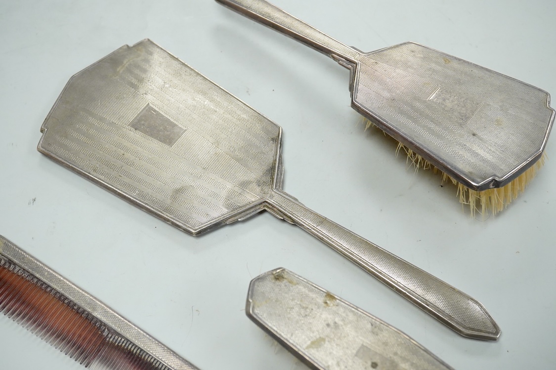 An Elizabeth II engine turned silver Art Deco style four pieced dressing table mirror, brush and comb set, W.I. Broadway & Co, Birmingham, 1961/63/65, mirror 27.8cm.